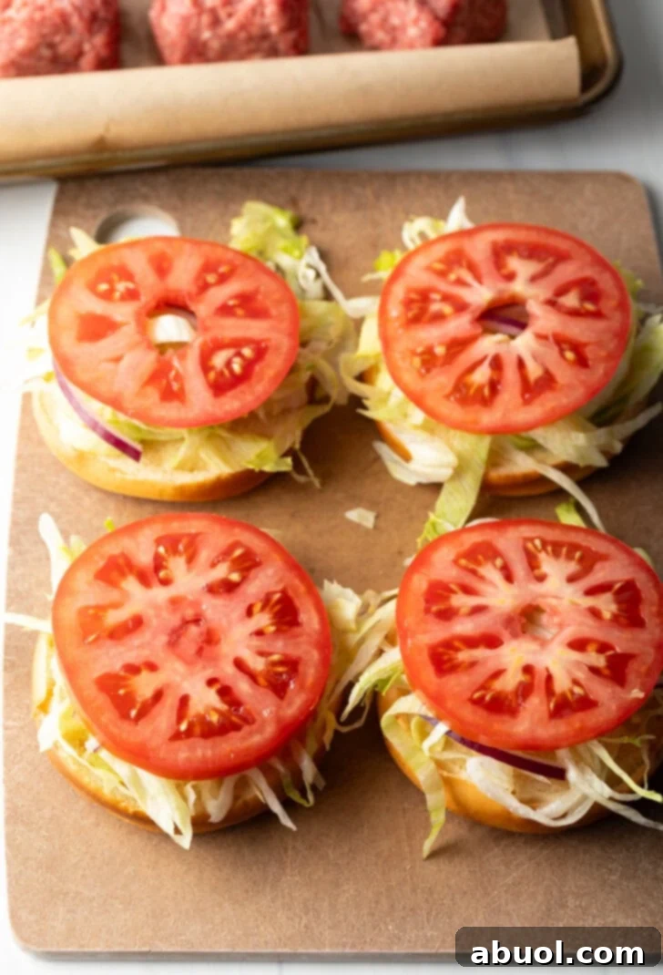 4 burgers topped with slices of tomato.