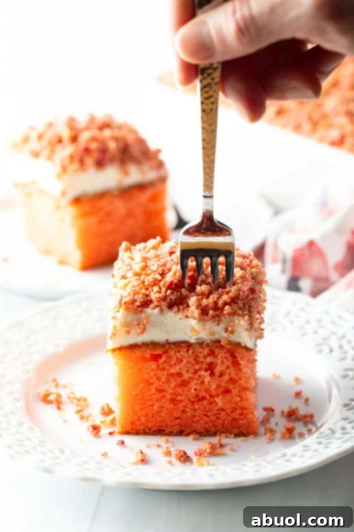 Berry Crumble Bliss Cake 15 A fork piercing into a delectable square of strawberry crunch cake, perfectly poised for a bite, on a clean white plate.