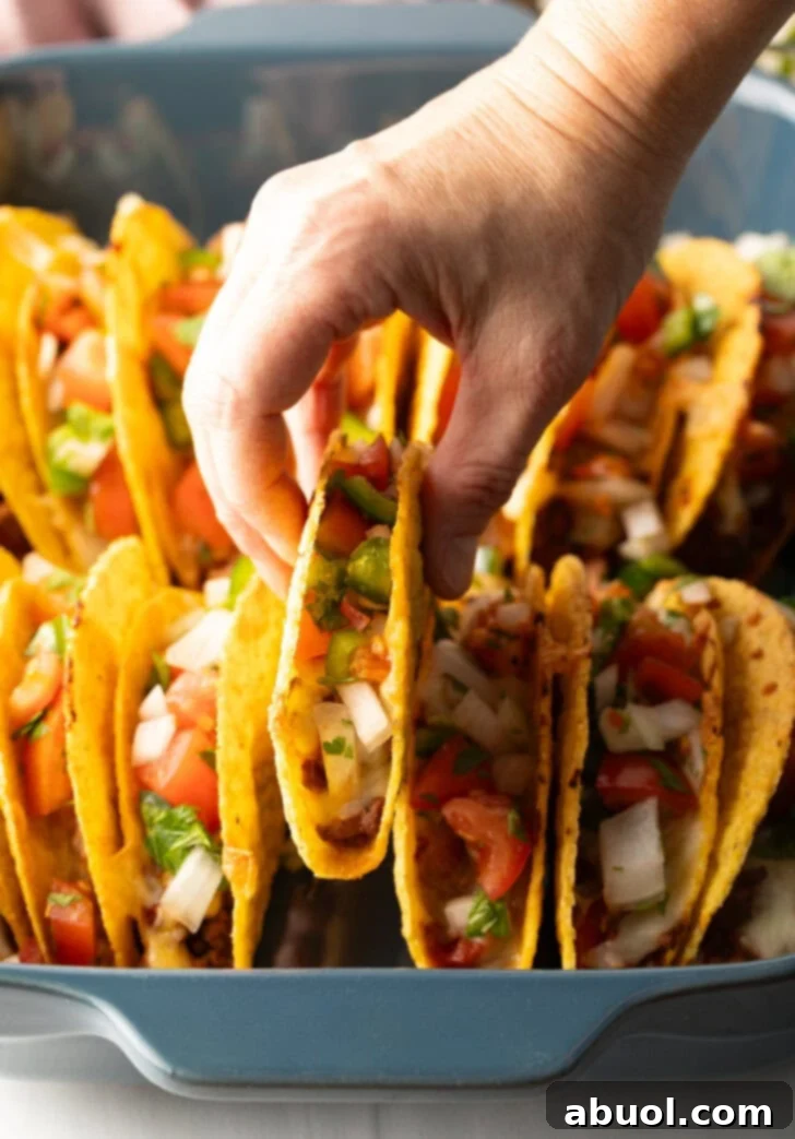 Hand picking up a taco from the tray.