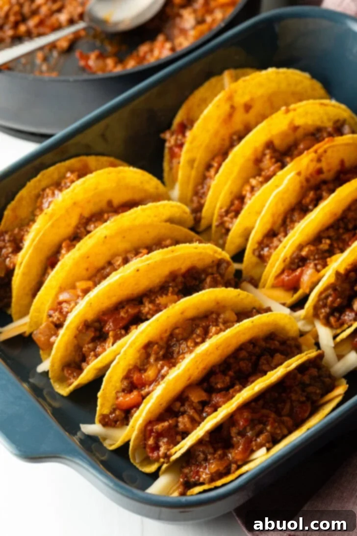 Ground beef mixture added to yellow corn tortilla shells.