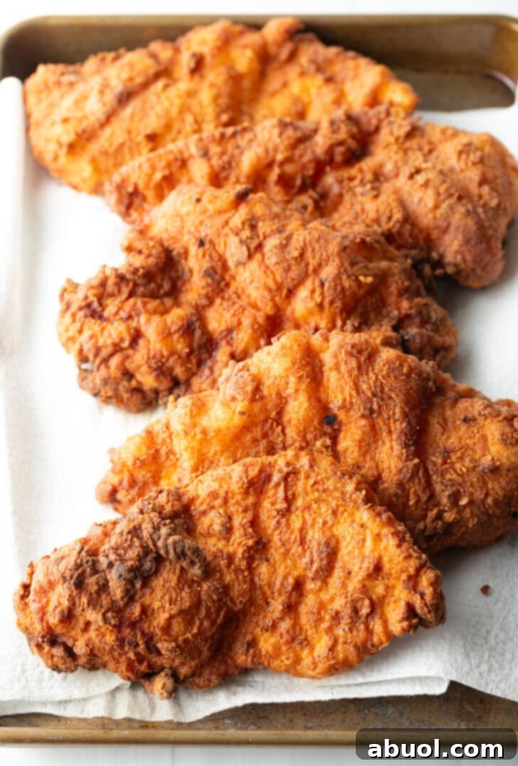 Blazing Honey Chicken 9 Five pieces of freshly fried, golden-brown chicken breasts resting on a stack of paper towels, allowing excess oil to drain after frying.