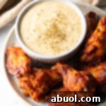 Plate of chicken wings with ramekin of garlic parmesan sauce.