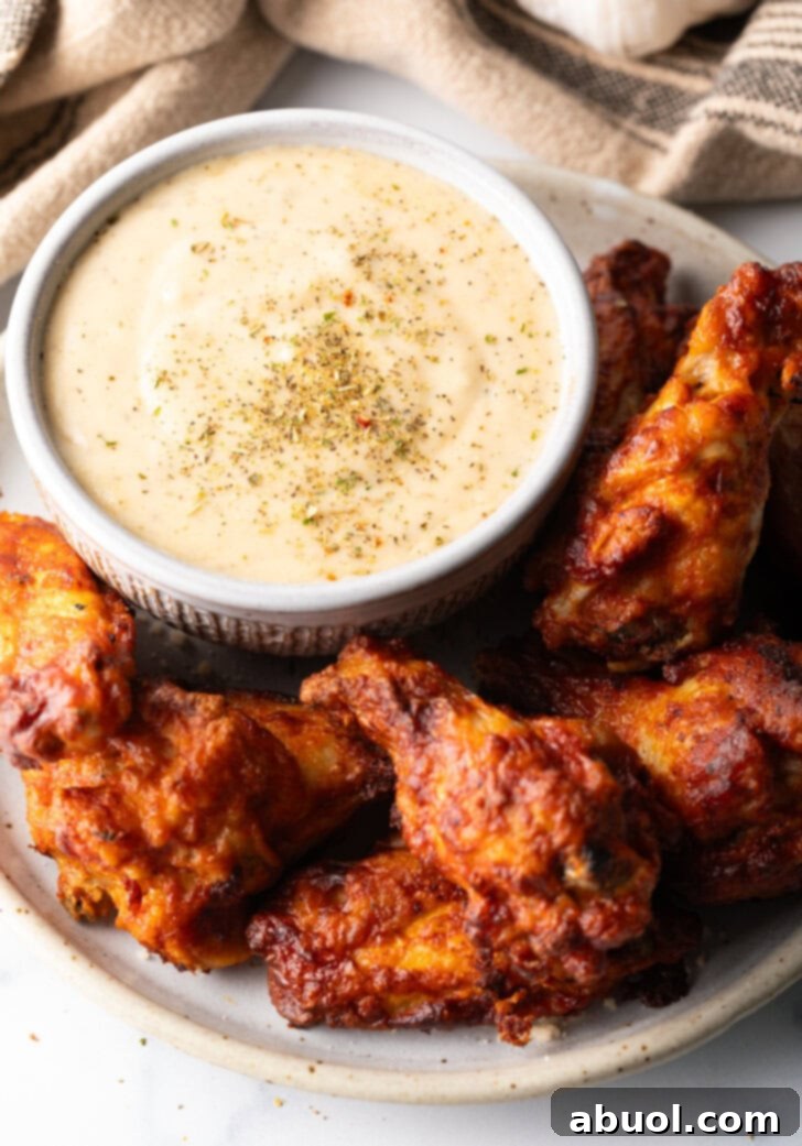 Plate of chicken wings with ramekin of garlic parmesan sauce.