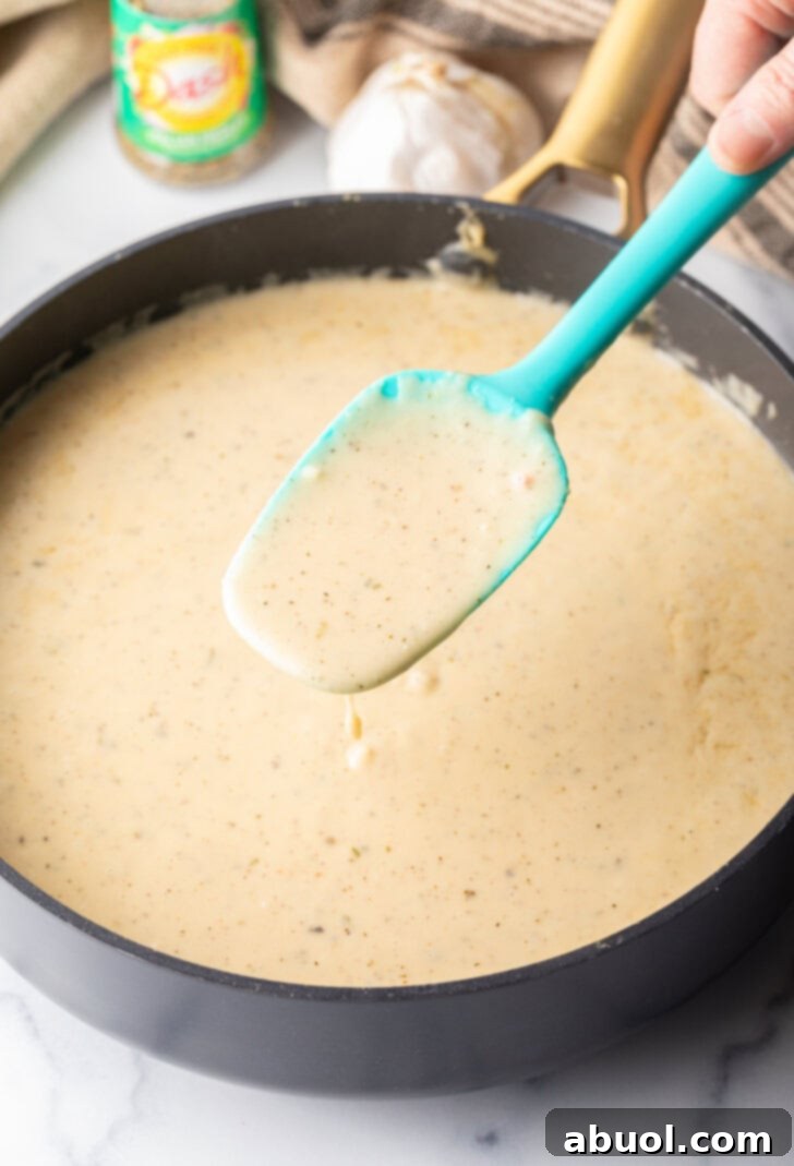 Blue spatula stirring sauce in a skillet.