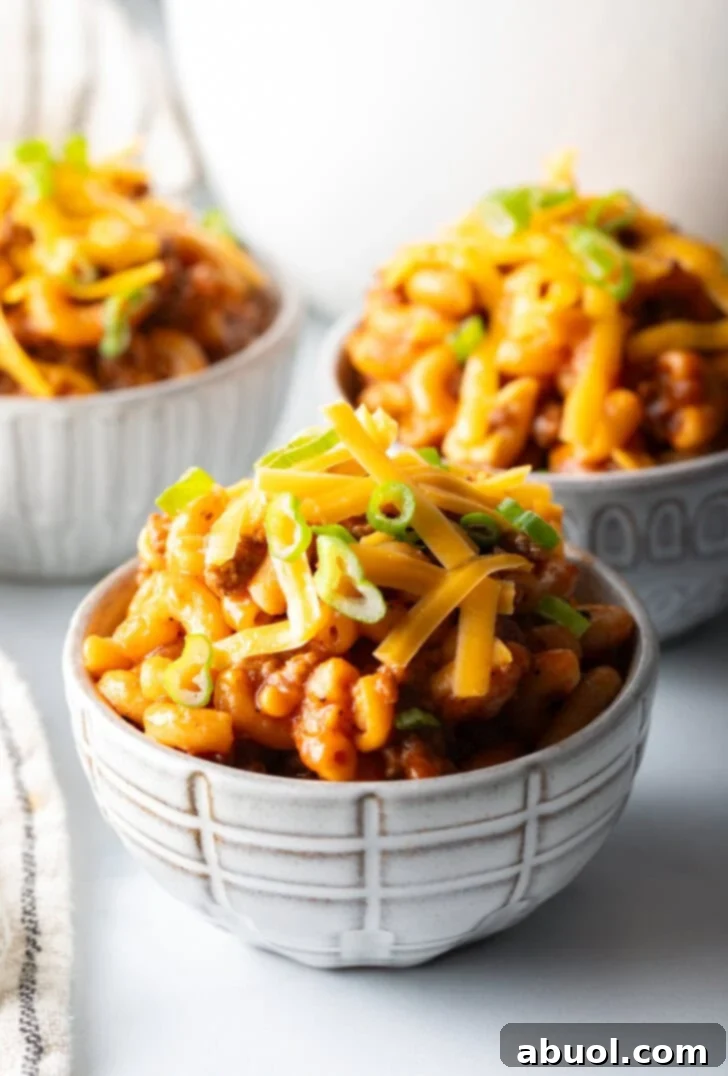 Hearty Beef and Macaroni Skillet 2 Three bowls of beefaroni topped with shredded cheddar cheese and chopped scallions, ready to be served.