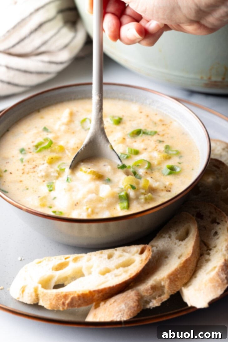 A spoon taking a scoop from a bowl of hearty fish chowder, showcasing its rich texture and ingredients.