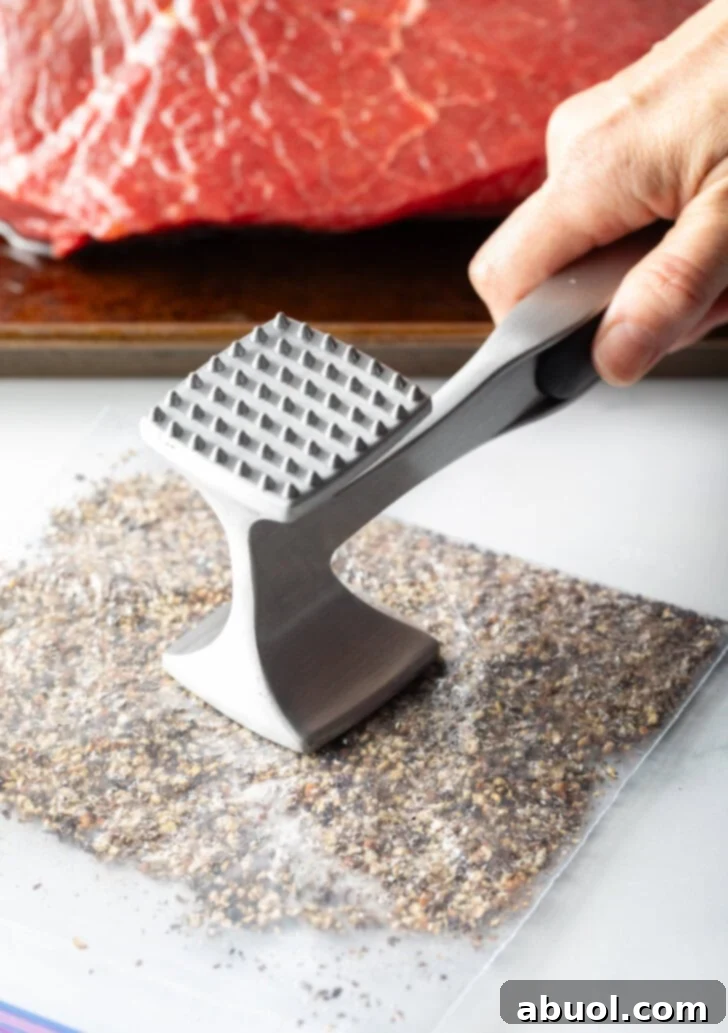 Classic Family Roast Beef 6 Hand with metal mallet smashed peppercorns in a plastic zipper bag.
