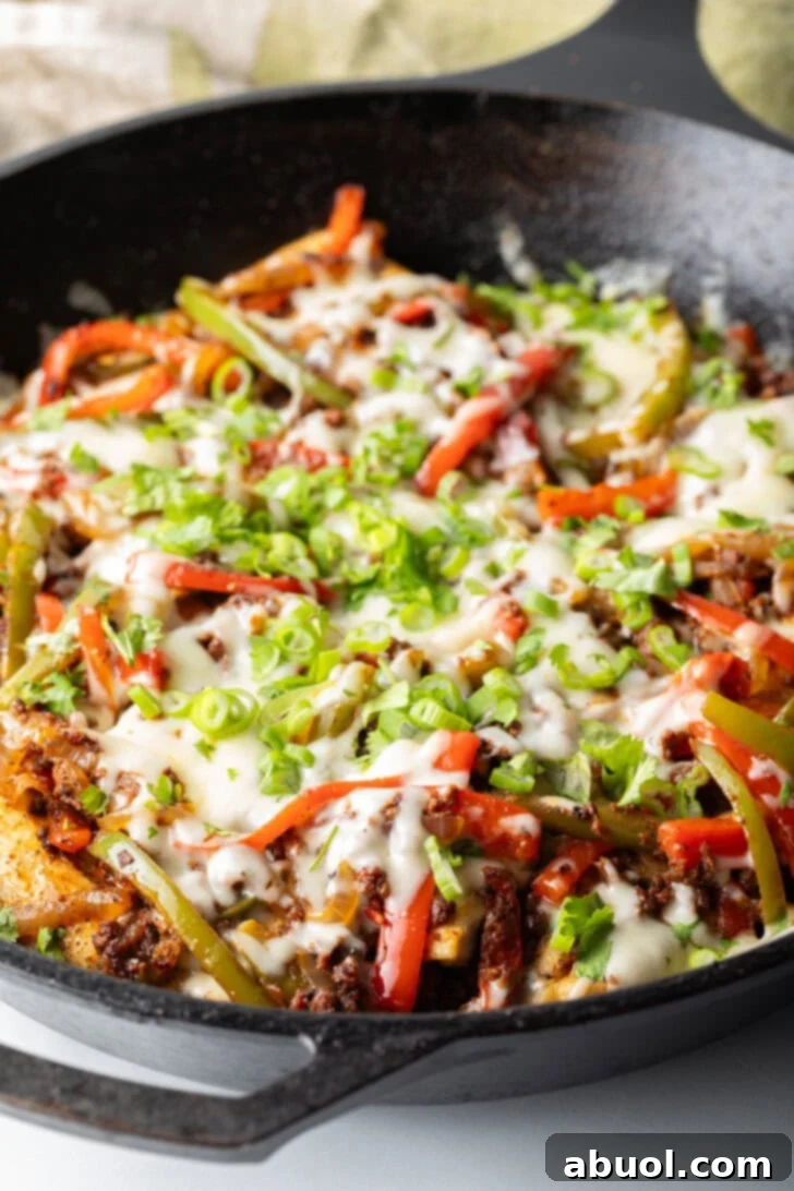 Choripollo in a black skillet, topped with cheese and green onions.