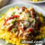 Chori pollo (chicken chorizo) covered in cheese on a bed of yellow rice.