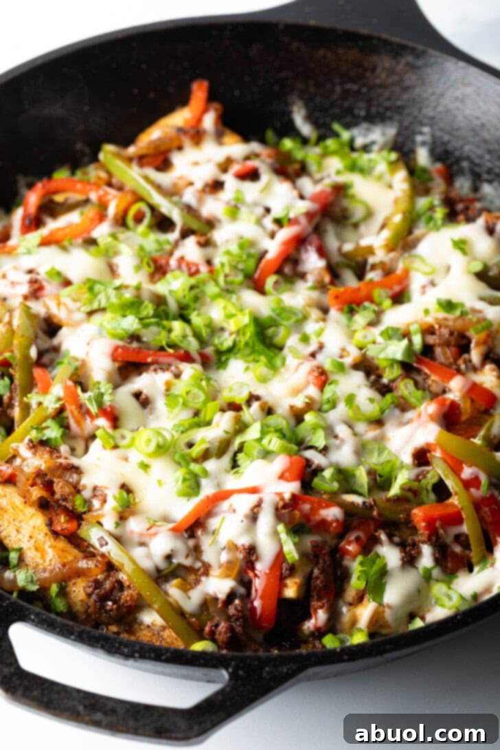 Choripollo in a black skillet, topped with cheese and green onions.