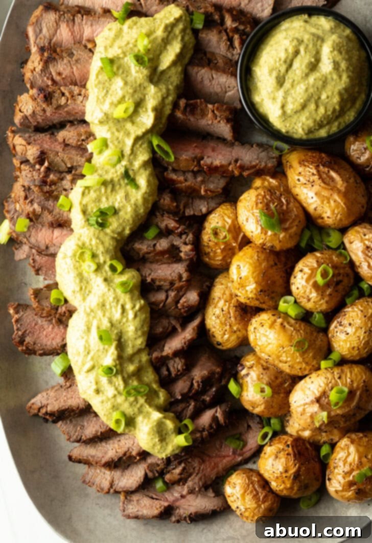 London broil sliced into thick strips, covered with rich green sauce and chopped scallions with baby potatoes on the side.