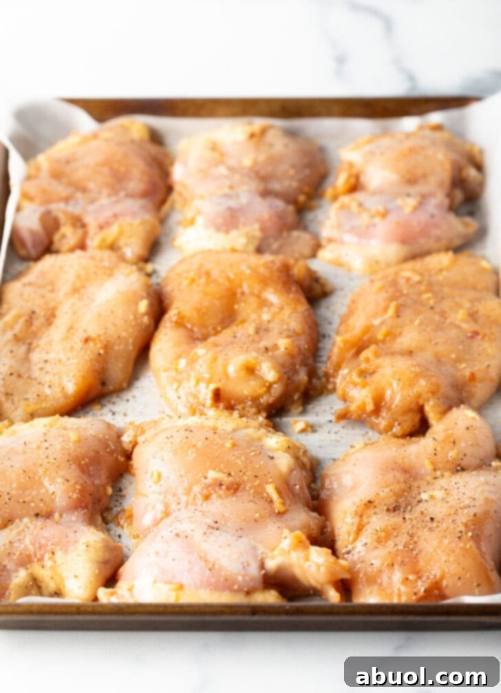 9 raw chicken thighs on a baking sheet.