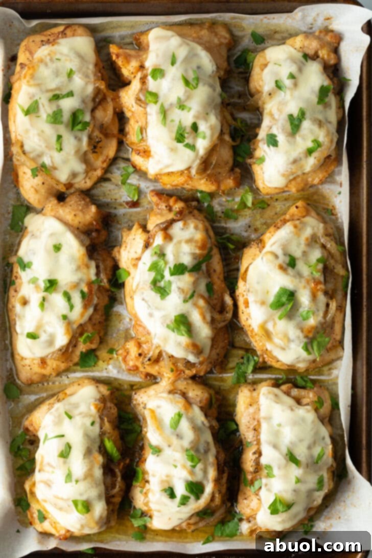 9 chicken thighs on a baking sheet topped with melted provolone cheese.