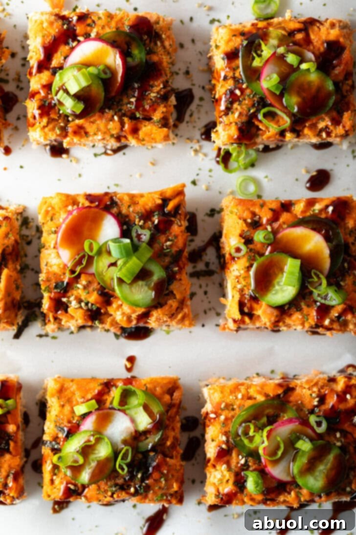 Rows of perfectly cut square slices of salmon sushi bake, artfully garnished, presented on a baking sheet.