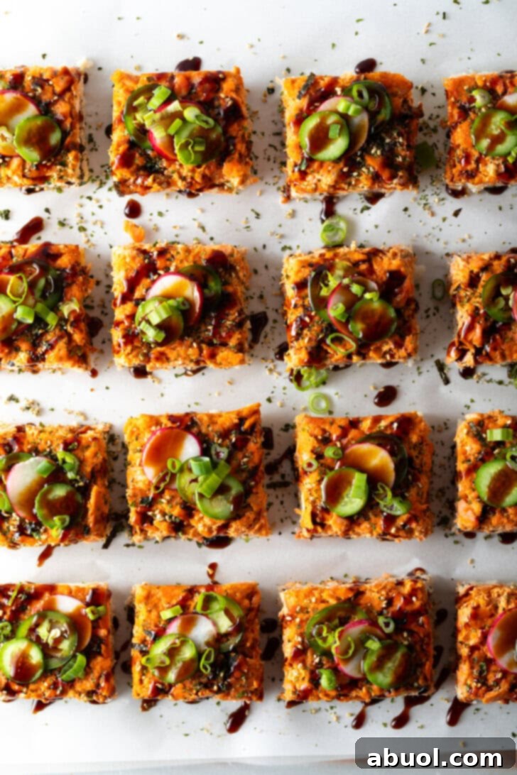 Rows of perfectly square slices of salmon sushi bake arranged on a baking sheet, beautifully presented and ready to be served.