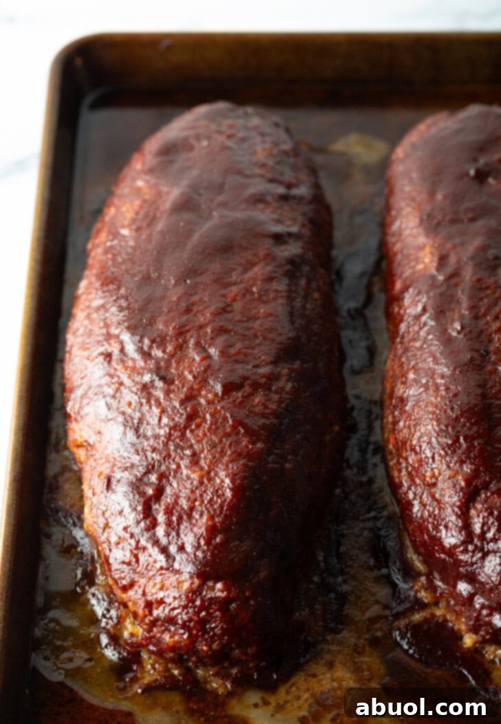 Slow Smoked Meatloaf 11 A top-down shot of two perfectly cooked, glistening smoked meatloaves fresh out of the smoker. Their dark, caramelized barbecue crust is evident, promising rich flavor.