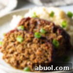 Slow Smoked Meatloaf 14 Two slices of meatloaf on a plate with a scoop of mashed potatoes, all topped with chopped green onions for garnish.