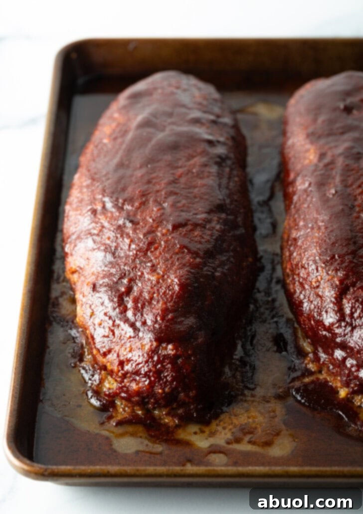 Slow Smoked Meatloaf 4 A top-down view of two beautifully browned meatloaves, fresh out of the smoker. Their tops are glazed with a rich barbecue sauce, promising a succulent and smoky flavor experience.