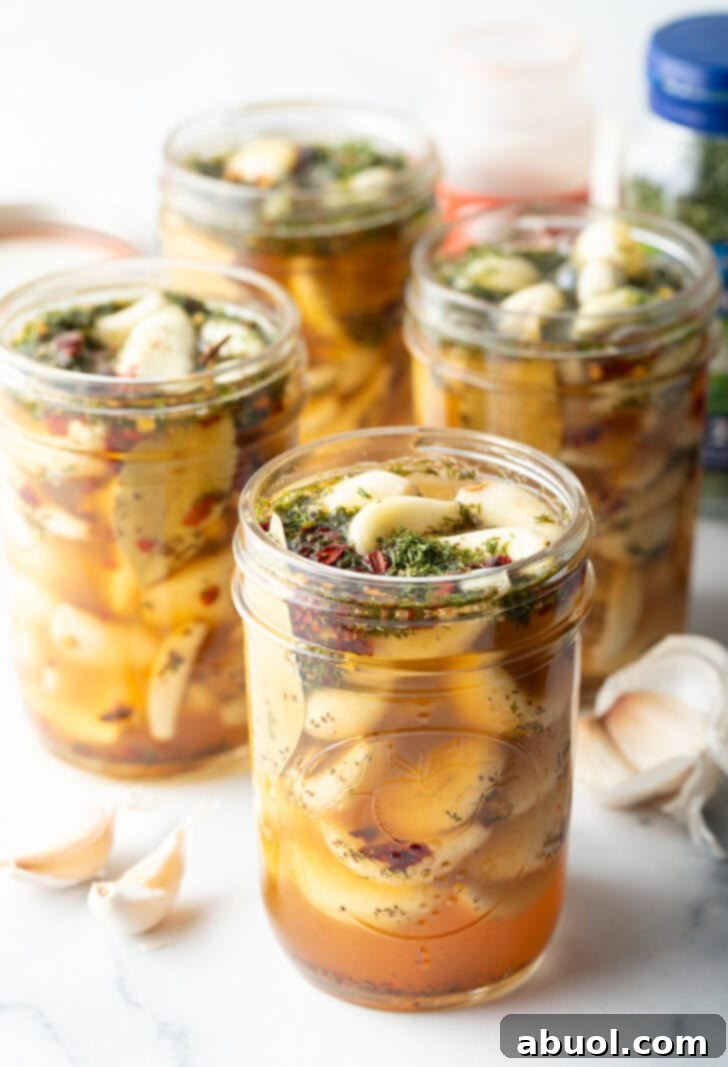 Several open glass jars stuffed with preserved garlic and herbs.