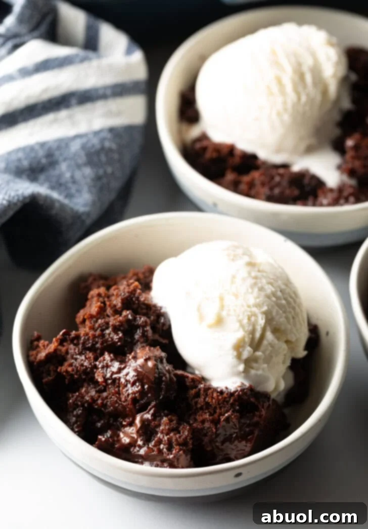 White bowl with serving of chocolate lava cake and a scoop of vanilla ice cream.