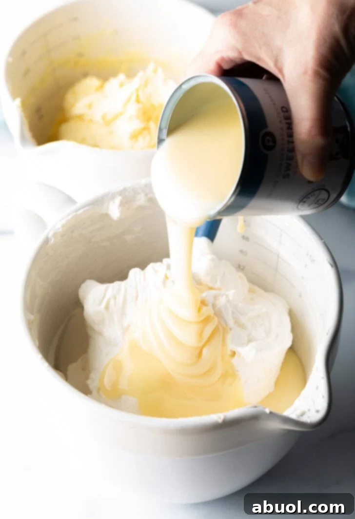 No-Churn Banana Pudding Dream 6 Hand pouring can of condensed milk over ingredients in the mixing bowl.