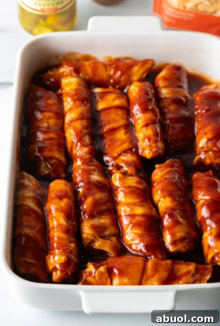 White baking dish filled with raw stuffs shells, all coated in bbq sauce.