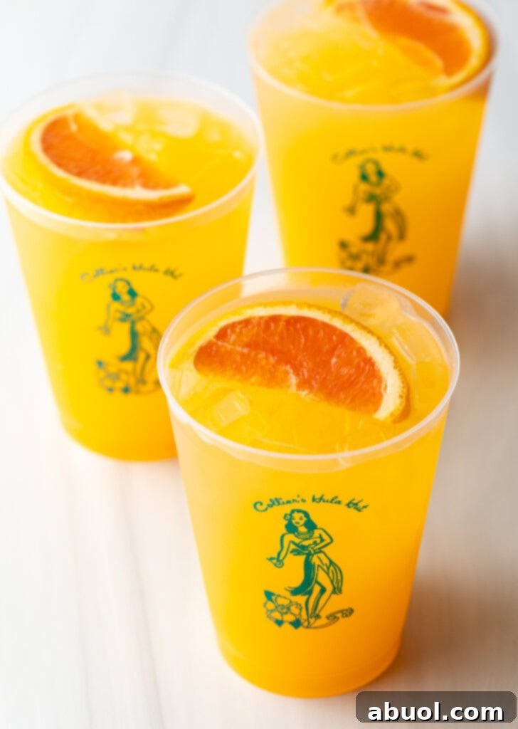 Three perfectly garnished Sunny D Vodka Seltzer drinks in glasses, waiting to be served.
