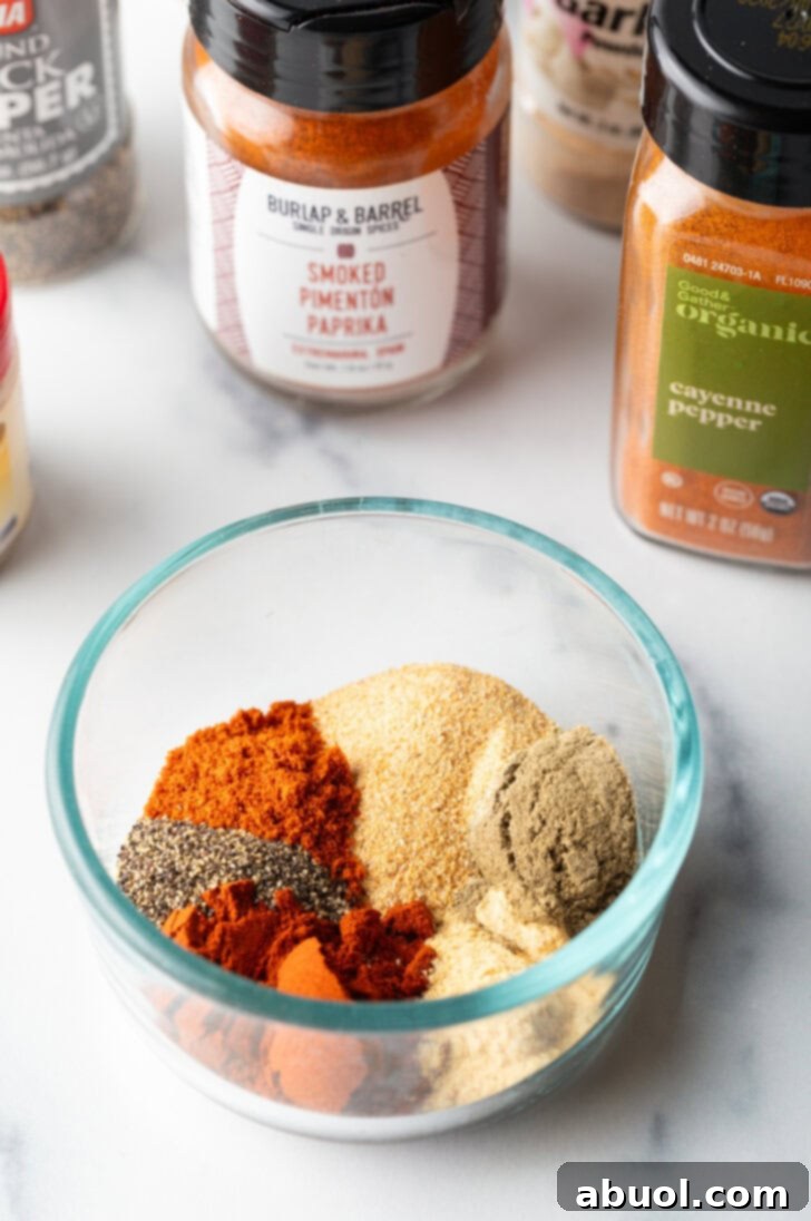 Glass bowl with assortment of smoked turkey rub spices: garlic, paprika powder, sage, onion powder, black pepper, cayenne pepper.
