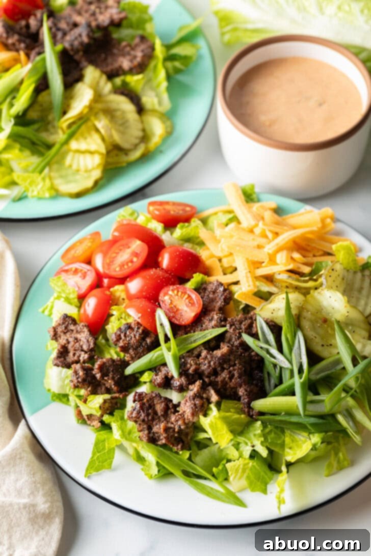 A close-up of a meticulously arranged Big Mac cheeseburger salad, featuring vibrant green lettuce, rich ground beef, bright red tomatoes, shredded cheese, and distinct pickle slices, all perfectly garnished and ready to eat.