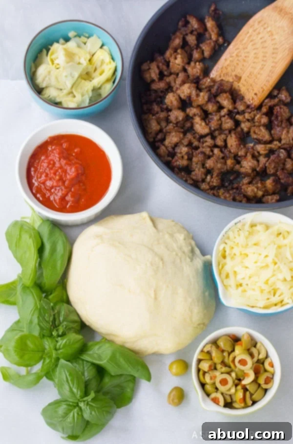 Fresh ingredients laid out for Stromboli: pizza dough, marinara sauce, fresh basil, artichoke hearts, green olives, cooked Italian sausage, and shredded mozzarella cheese.
