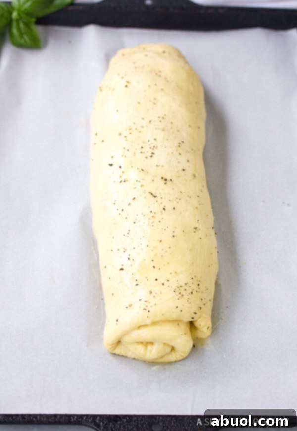 Close-up of the rolled pizza dough, filled with ingredients, ready to be baked into Stromboli.