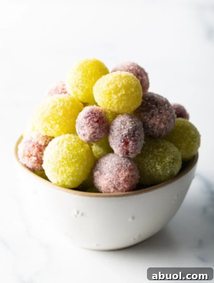 A close-up shot of a bowl brimming with perfectly coated green and purple candy grapes, ready to be enjoyed.