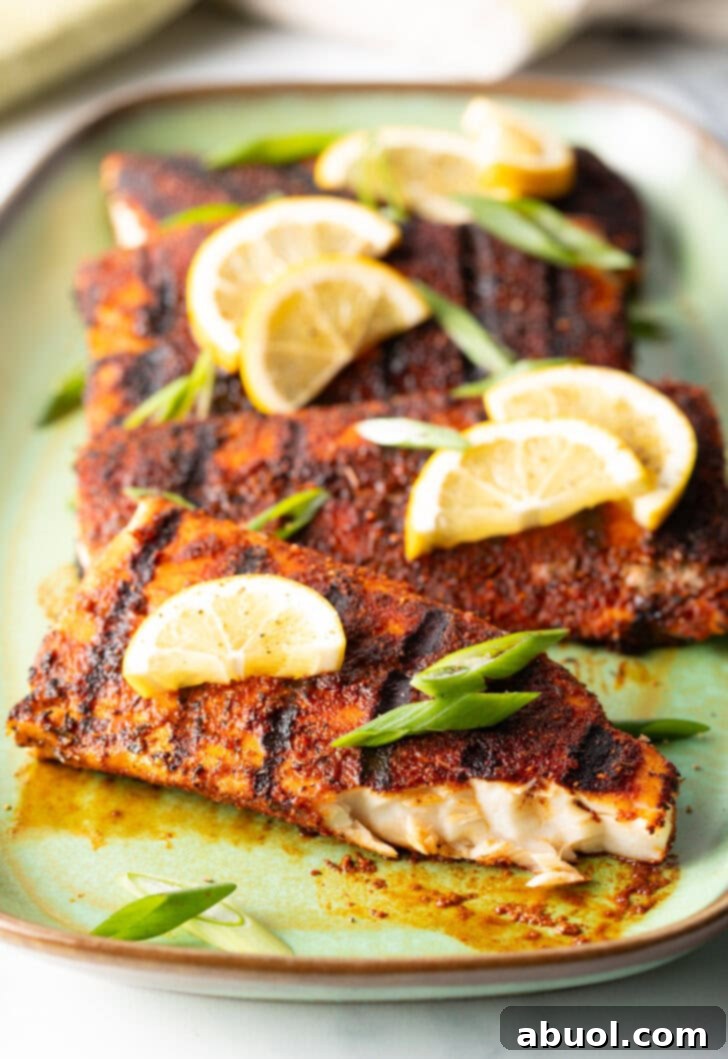 4 fillets of grilled mahi mahi topped with a slice of lemon and green onions. A bite has been removed from the fish to show the white flaky inside of the meat.
