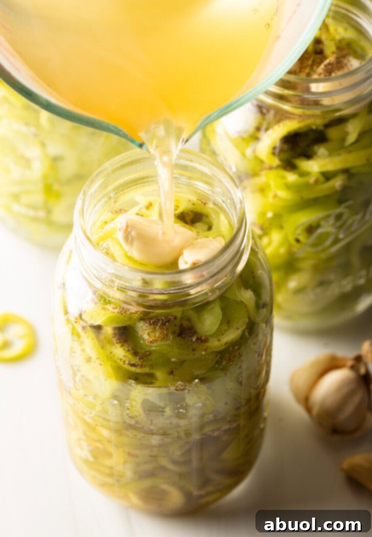Pouring pickling brine into a jar of sliced peppers.