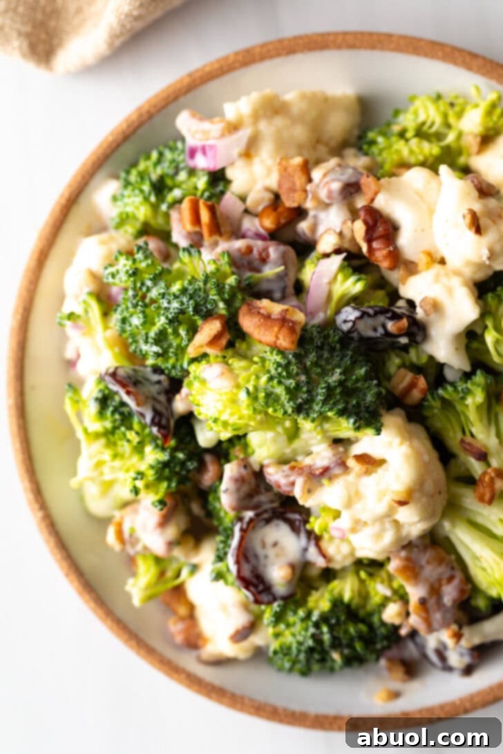 A beautiful top-down view of the creamy broccoli and cauliflower salad in a large glass serving bowl, showcasing its vibrant ingredients.