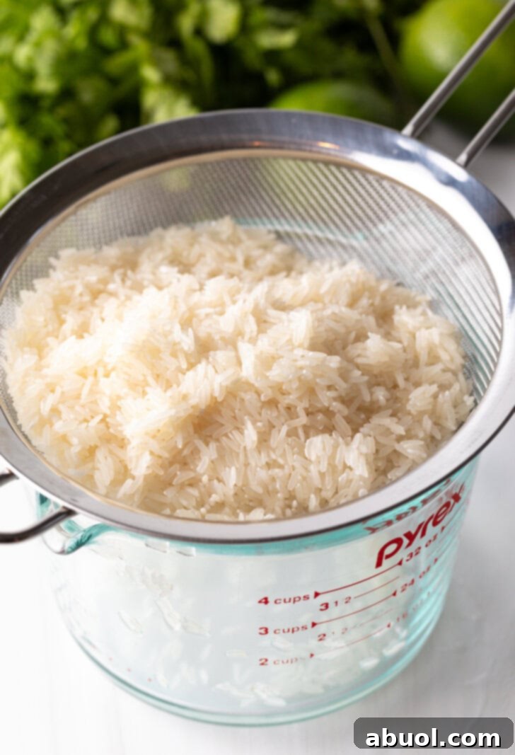 Straining white rice over a glass measuring pitcher.