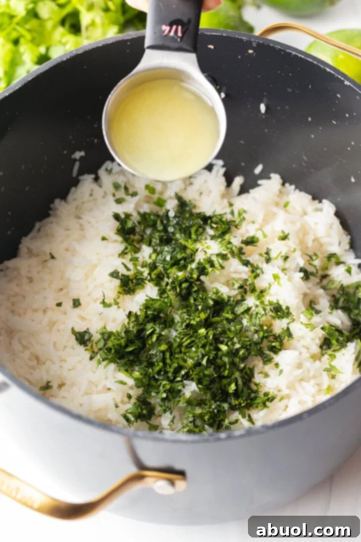 Adding lime juice from a measuring spoon over a pot with rice and chopped cilantro.