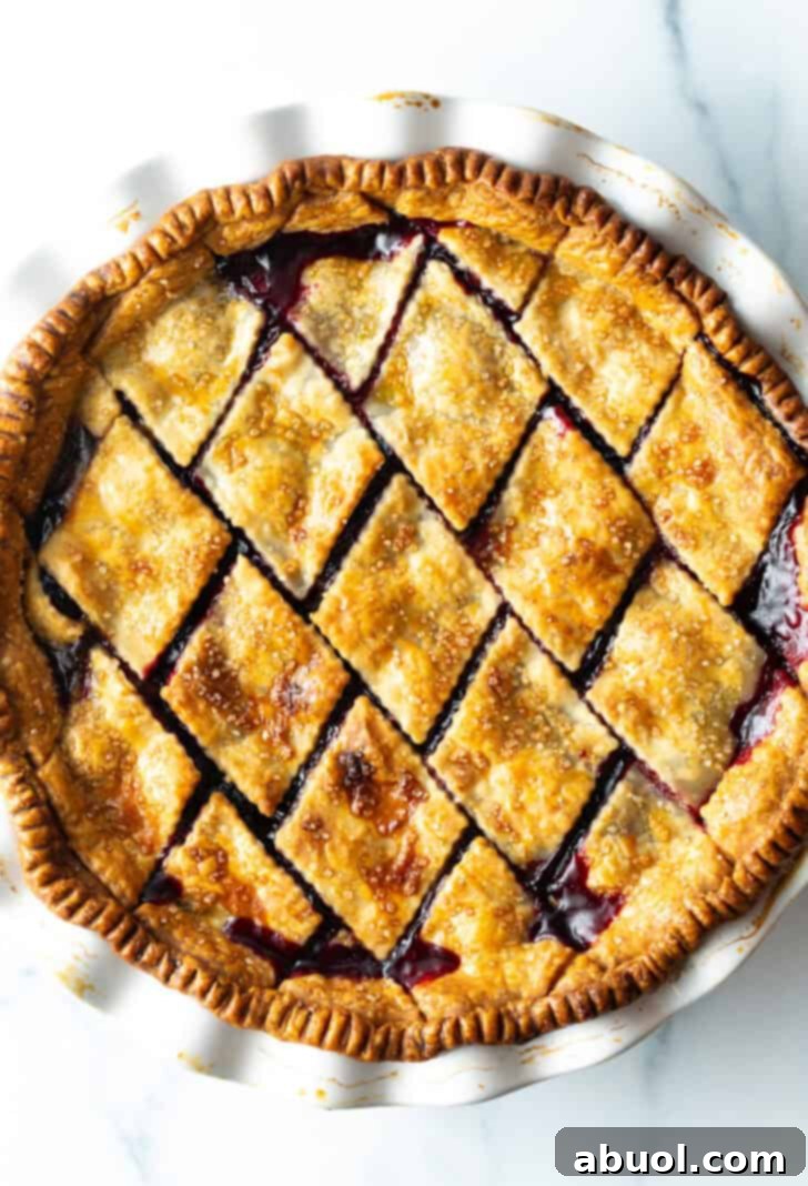 Top down view finished baked pie with diamond pattern crust with homemade cherry pie filling.