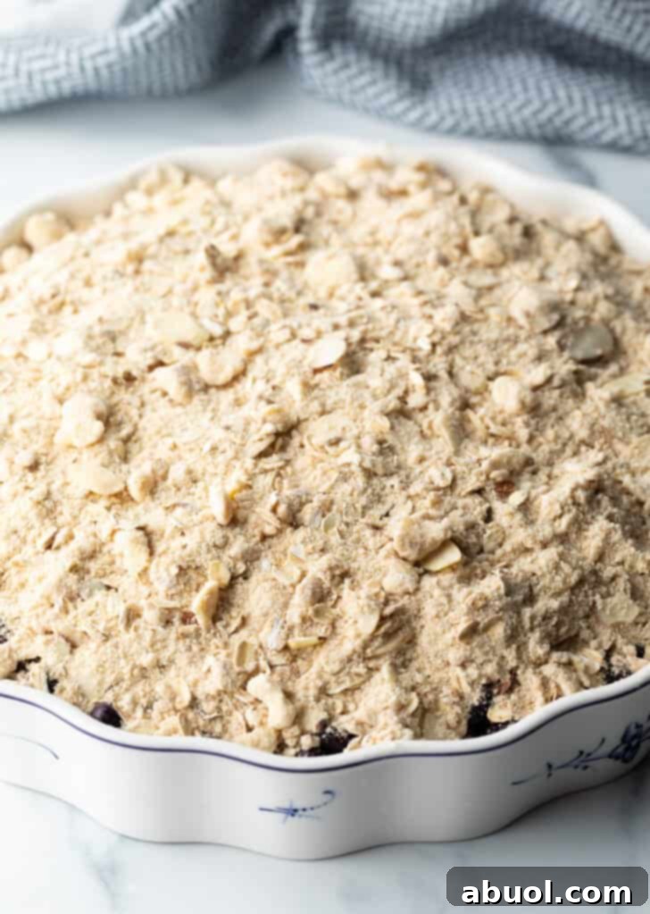 Raw crumble topping on top of the blueberries in a baking dish.