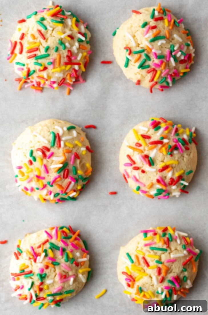Luscious Cream Cheese Delights 3 Top down view 6 cream cheese cookies on a baking sheet, each topped with sprinkles.