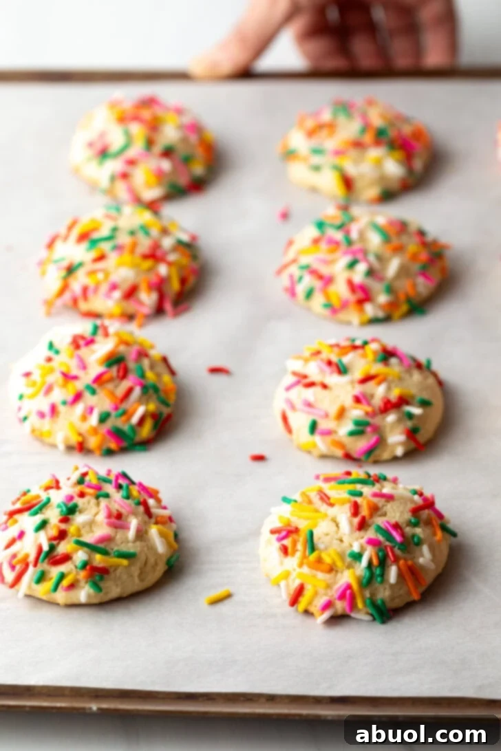 Luscious Cream Cheese Delights 8 8 cream cheese cookies on a baking sheet, each topped with sprinkles.