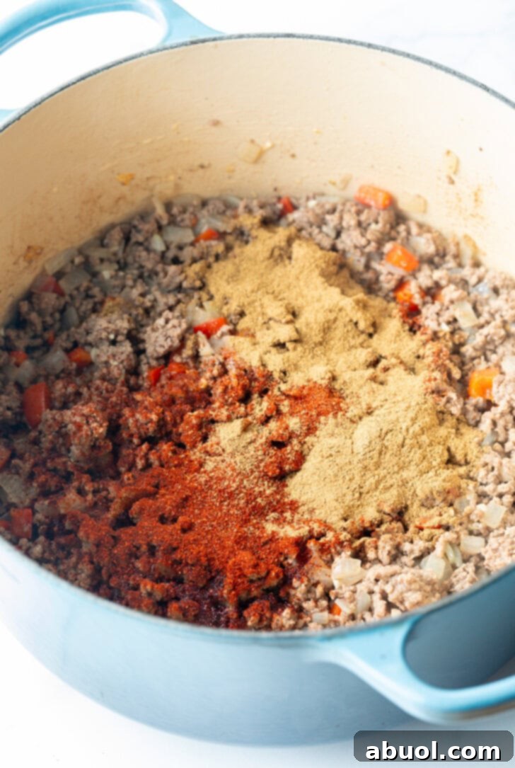 Cooked ground beef and spices in a large blue cooking pot.