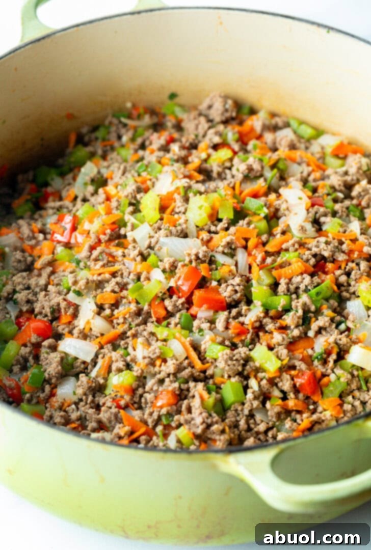 Cooking ground deer meat with chopped veggies in a large pot.