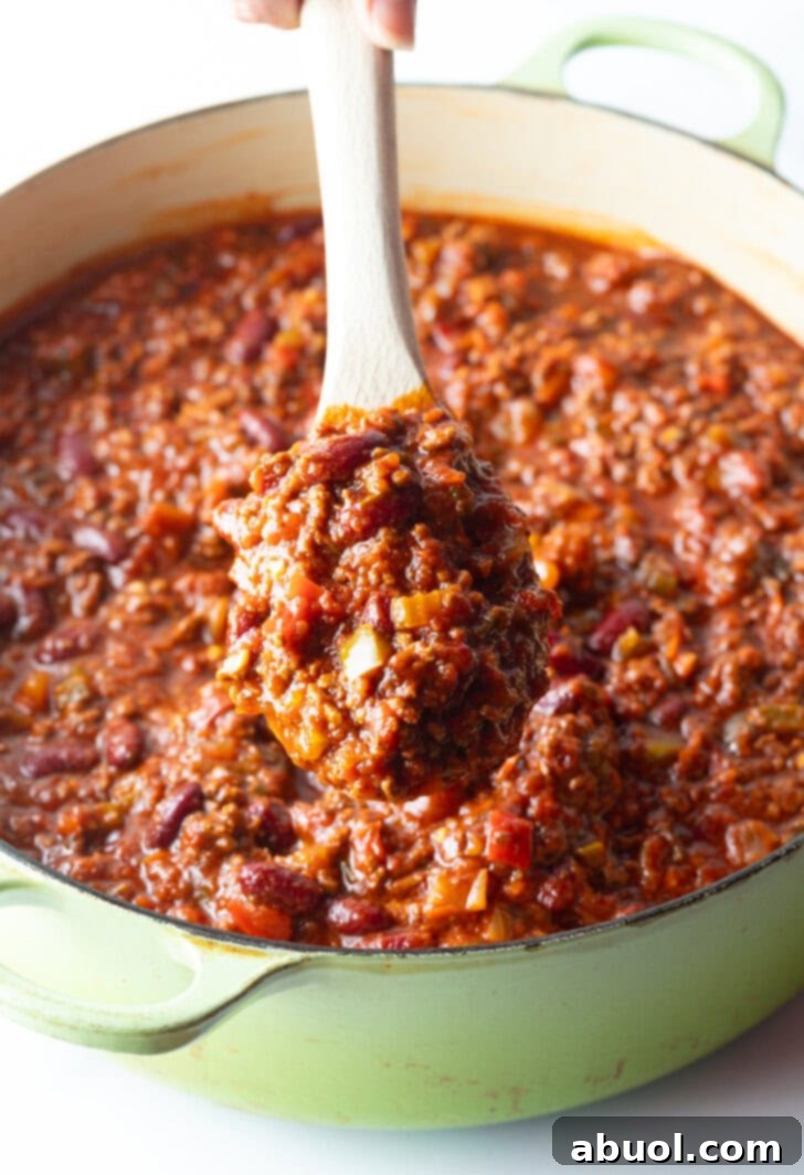 Close view of wooden spoon holding a scoop of meaty deer chili to camera.
