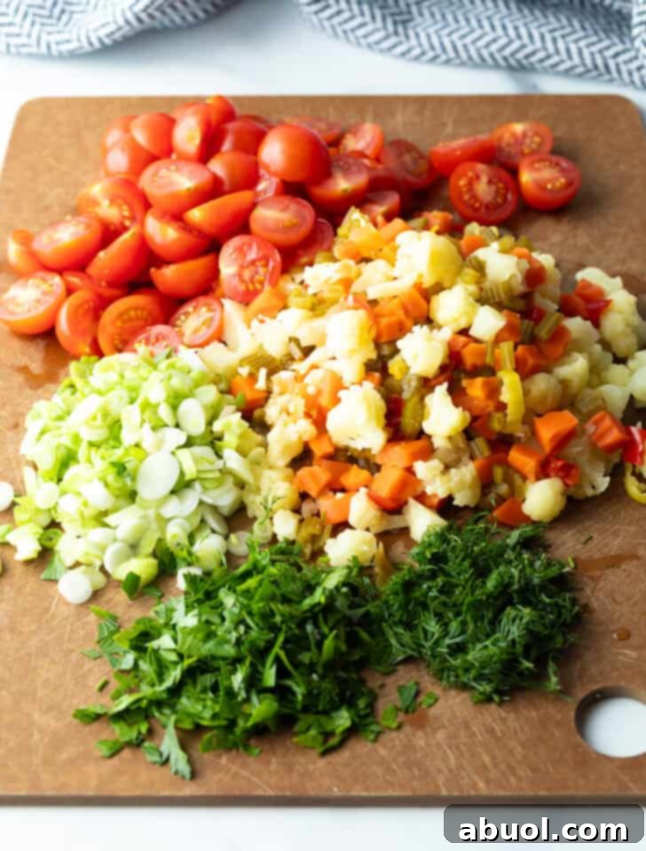 Chopped cherry tomatoes, scallions, fresh parsley, and pickled vegetables neatly arranged in piles on a rustic brown cutting board, showcasing vibrant ingredients.