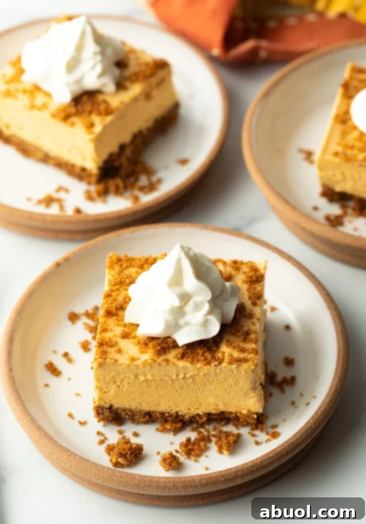 A single no-bake pumpkin cheesecake bar on a white plate, topped with a generous dollop of whipped cream, ready to be enjoyed.