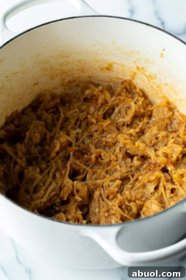 The same large cooking pot now filled with a generous amount of beautifully caramelized onion slices, showcasing their rich, golden-brown color.