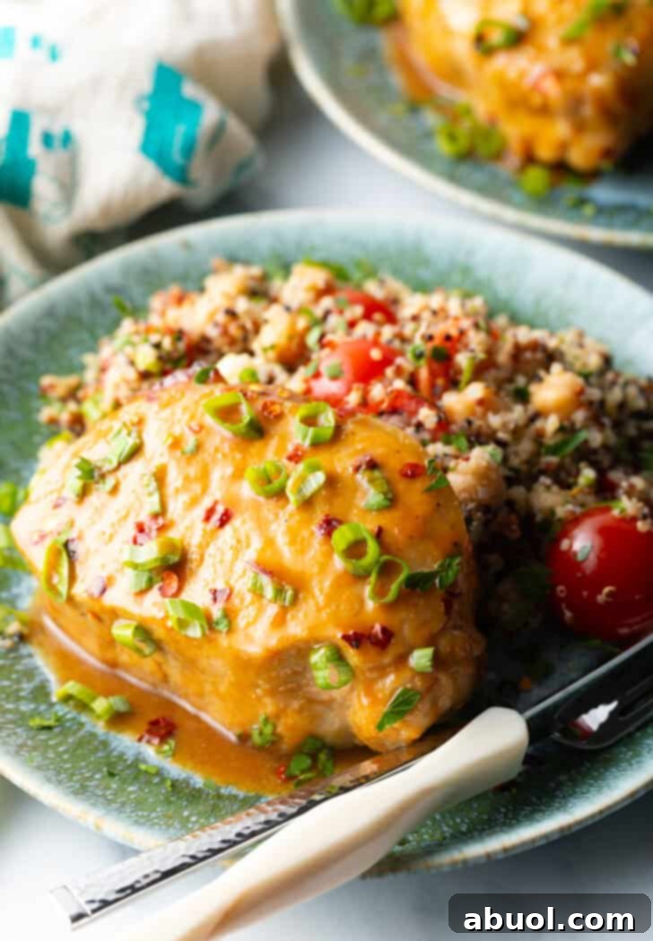 Perfectly Baked Pork Chops 2 Perfectly baked pork chop glistening with a savory glaze and sprinkled with fresh scallions, served alongside a vibrant quinoa and tomato salad.