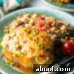 Baked pork chop covered with glaze and chopped scallions, on a plate next to quinoa salad with tomatoes.