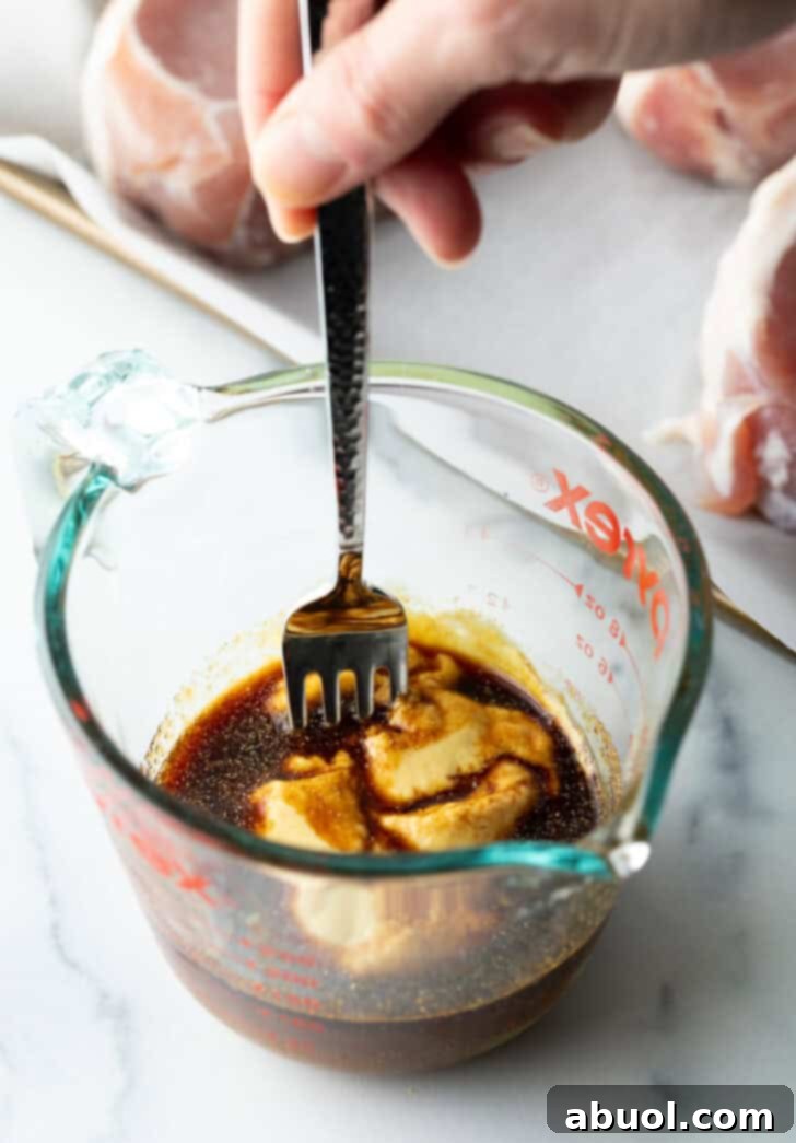 Perfectly Baked Pork Chops 5 Preparing the glaze: stirring together brown sugar, soy sauce, and Dijon mustard in a glass measuring cup with a fork.